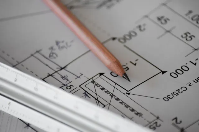 Engineering drawing with dimension lines under a drafting pencil