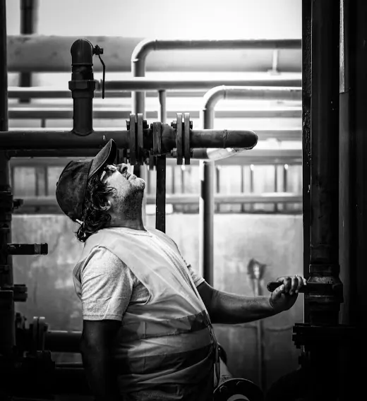 Technician adjusting a valve on overhead process piping